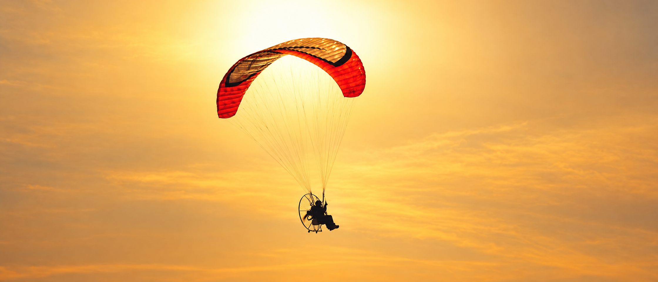 Paramotor flying into a sunset