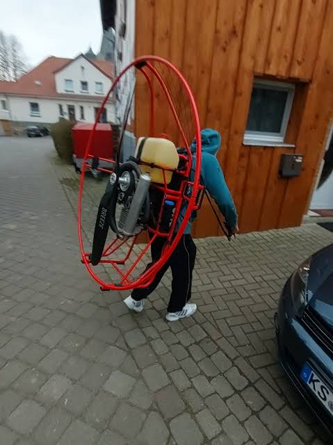 A pilot carrying a red paramotor